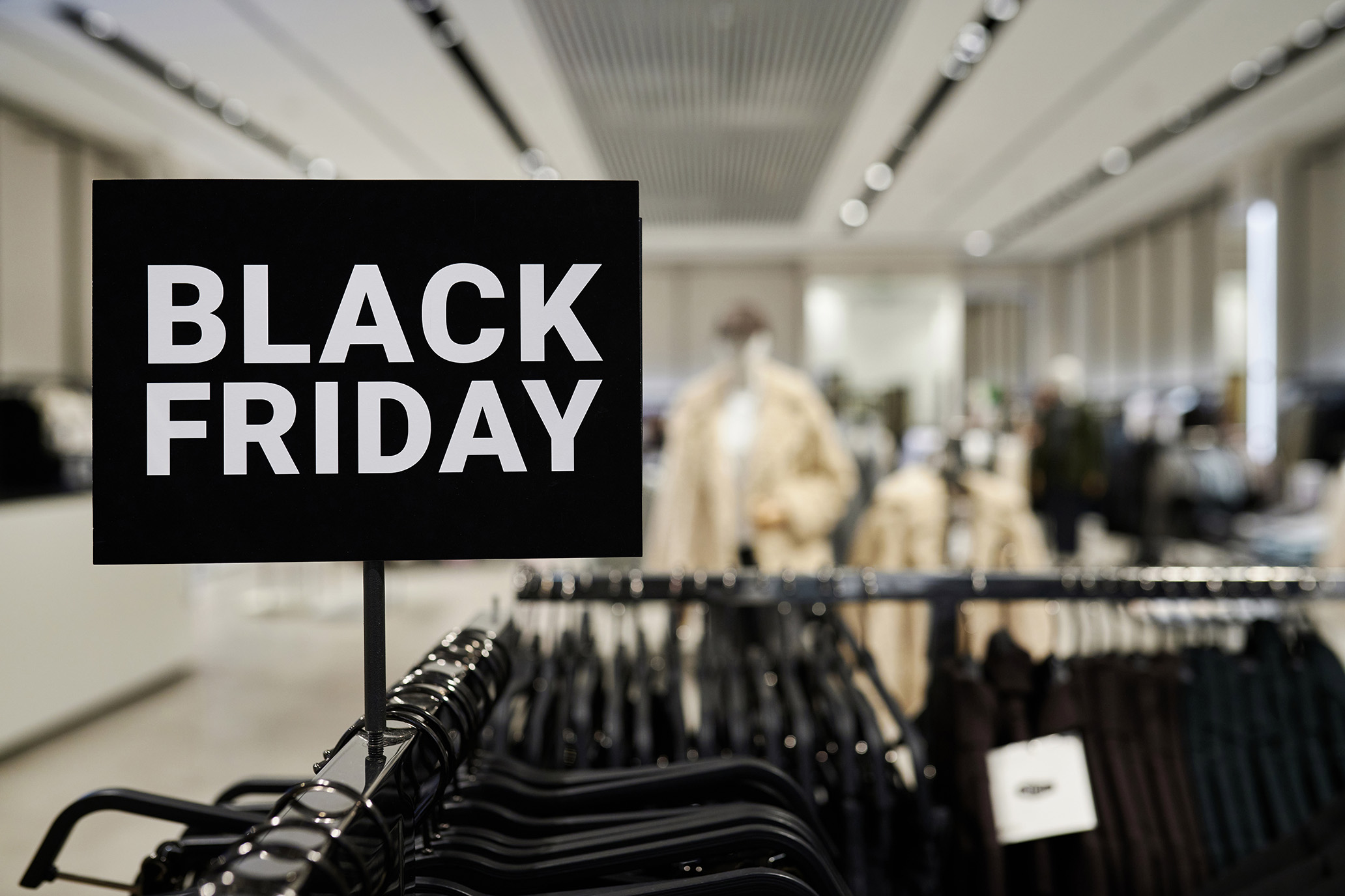 Black Friday sale sign displayed above clothing racks inside a modern retail store.